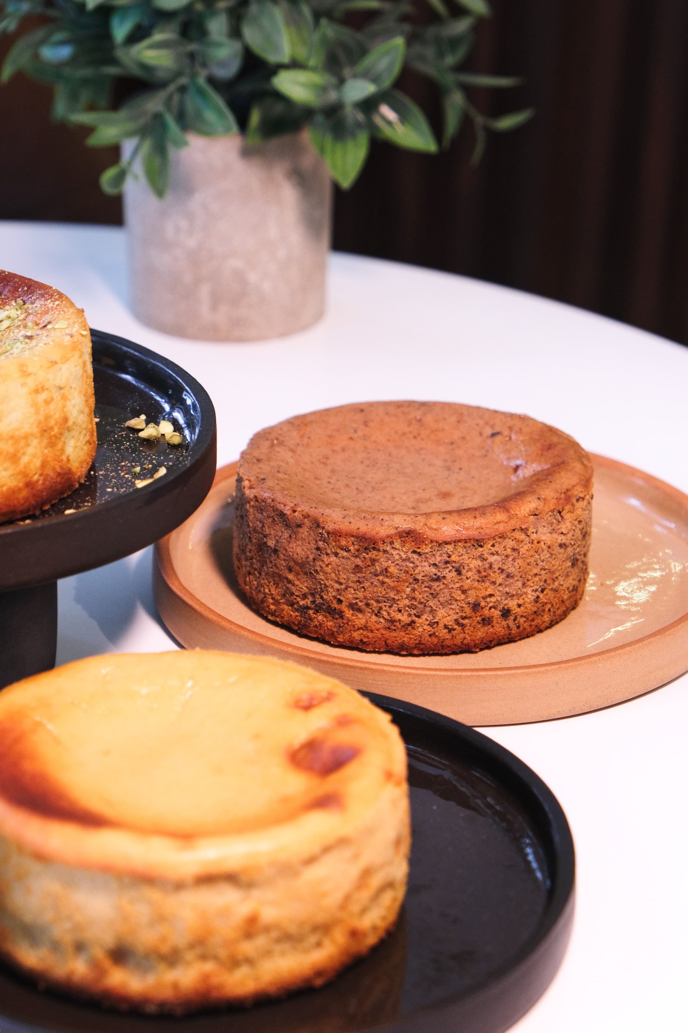 Tarta vasca entera junto a tazas de café con el logo de Gozo, sobre una mesa